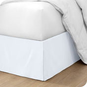 The corner of a bed with a bed skirt and comforter on it