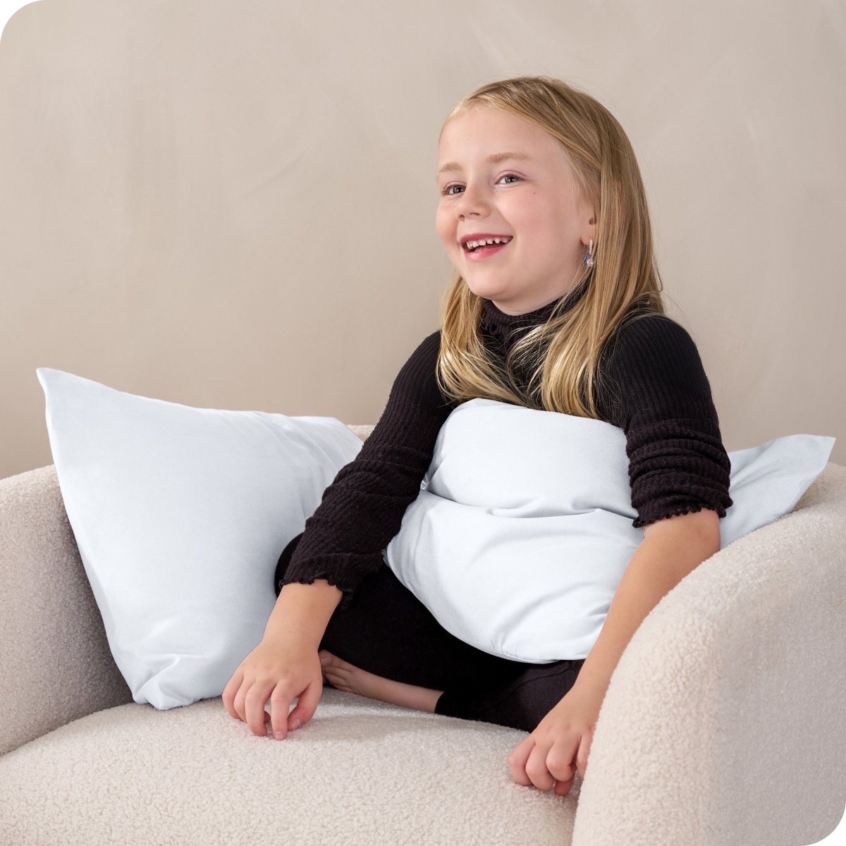 A child sitting while holding a microfiber pillowcase covered pillow