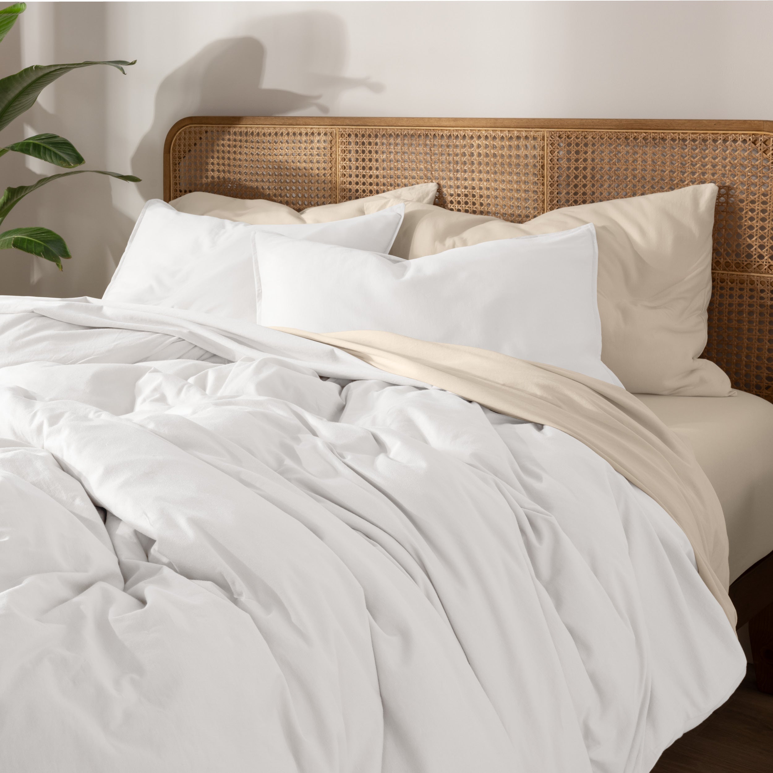 Bedding set on a bed with a wicker nightstand and lamp in a bedroom setting.