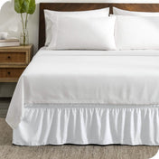 A wrap around bed skirt on a mattress with white bedding