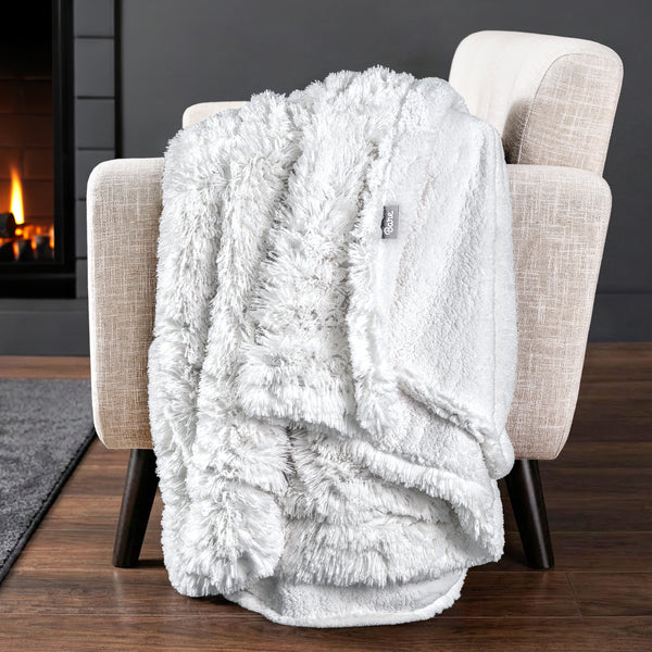 Sherpa blanket draped over an armchair in front of a fireplace.