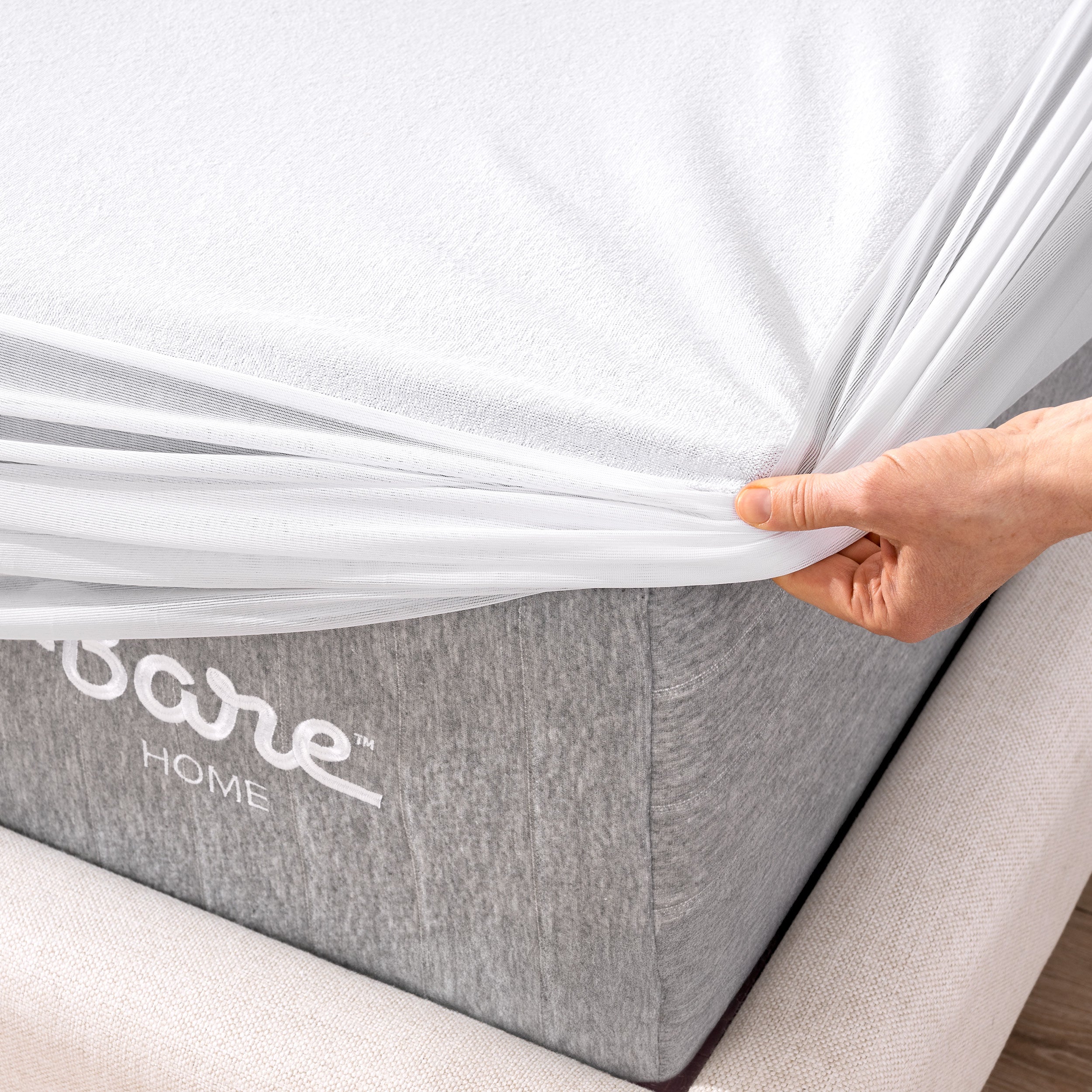 Close up of the corner of a mattress with a mattress protector being put on it