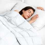 Woman sleeping peacefully under a weighted blanket with white pillows