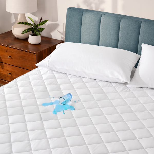 A glass of water spilled on a waterproof mattress pad
