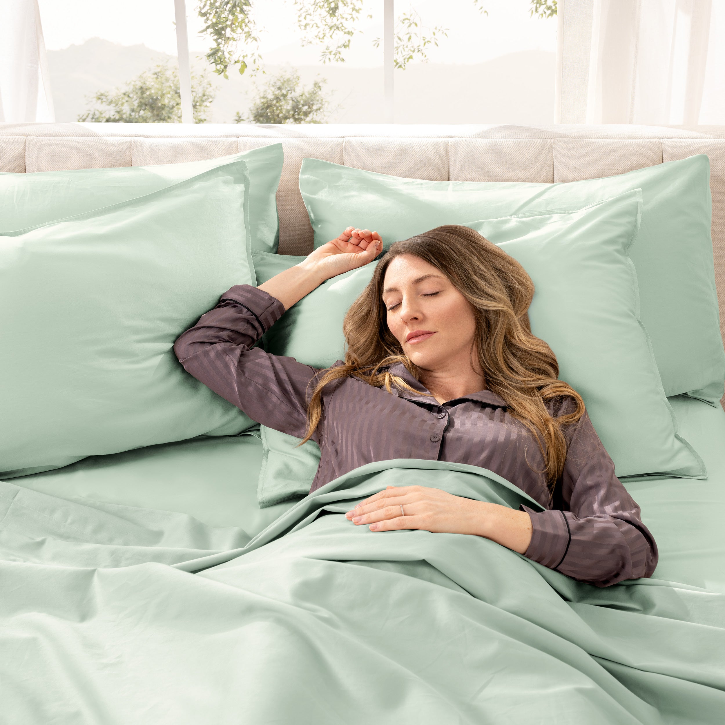 A woman is sleeping on a bed made with organic cotton sateen sheets