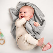 A baby lying on a receiving blanket. She has her thumb in her mouth.