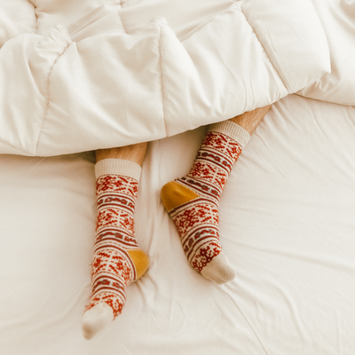 Closeup of feet in patterned socks resting on white bedding