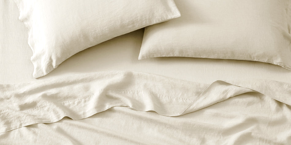 Linen sheets on a bed and linen pillowcases on pillows.