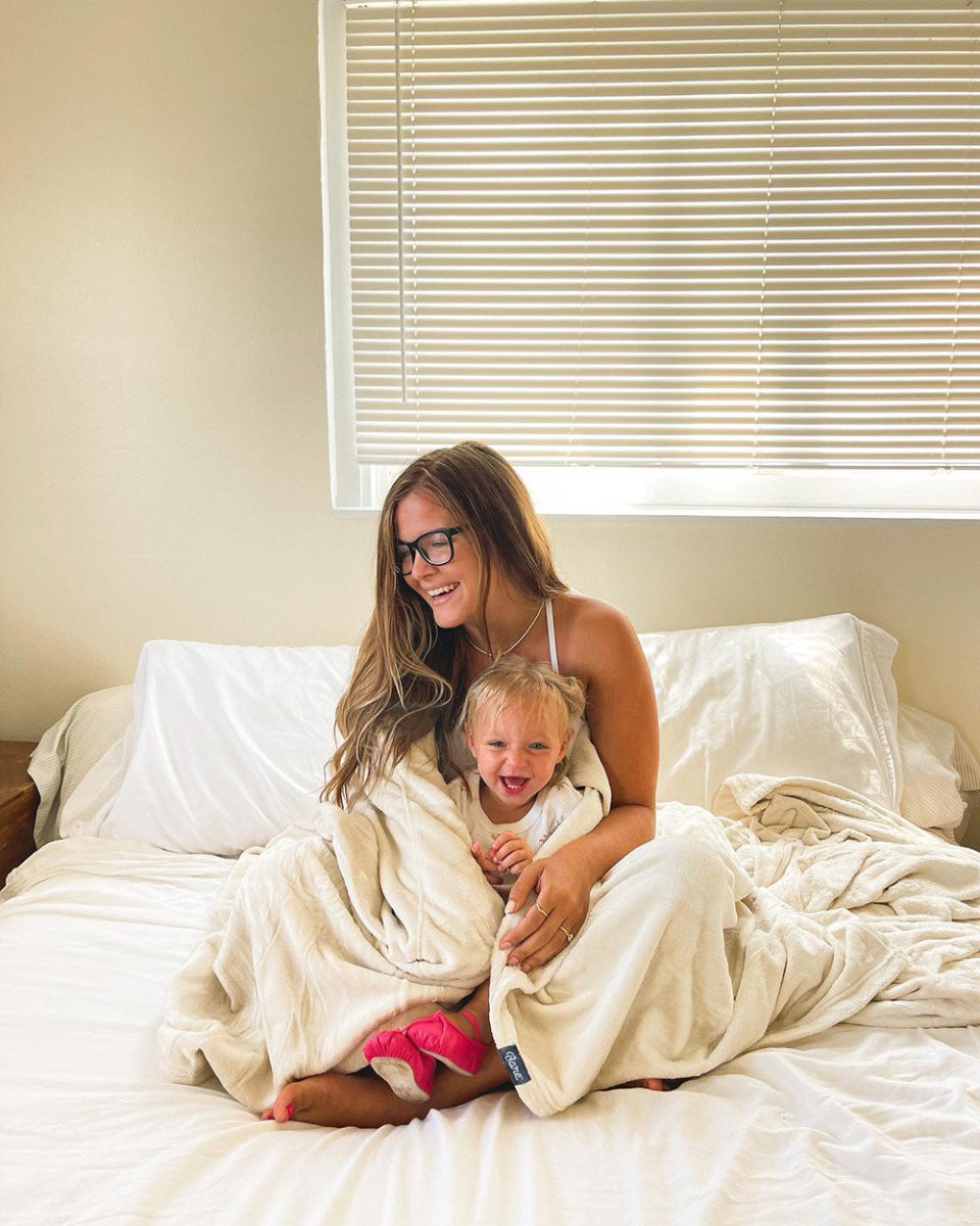 Mom with glasses hugging her daughter wrapped in a blanket 