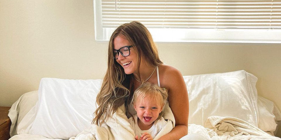 Mom with glasses hugging her daughter wrapped in a blanket 