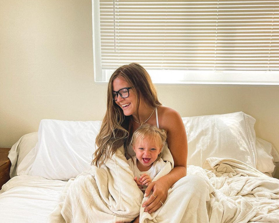 Mom with glasses hugging her daughter wrapped in a blanket 