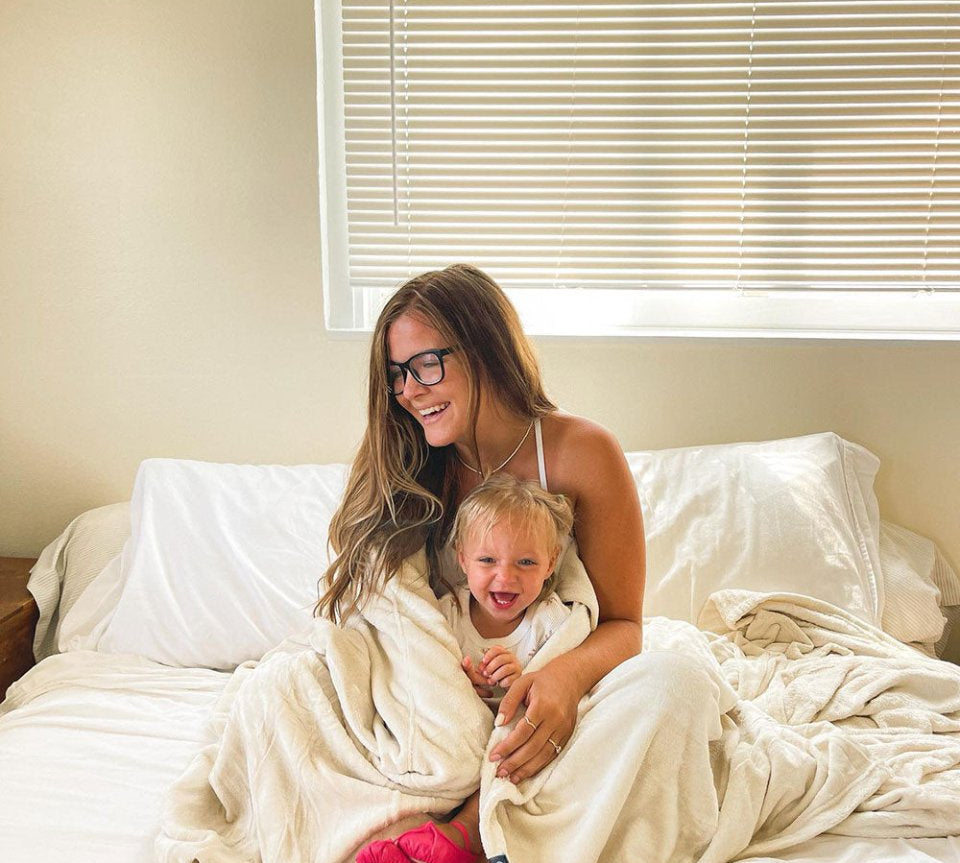 Mom with glasses hugging her daughter wrapped in a blanket 