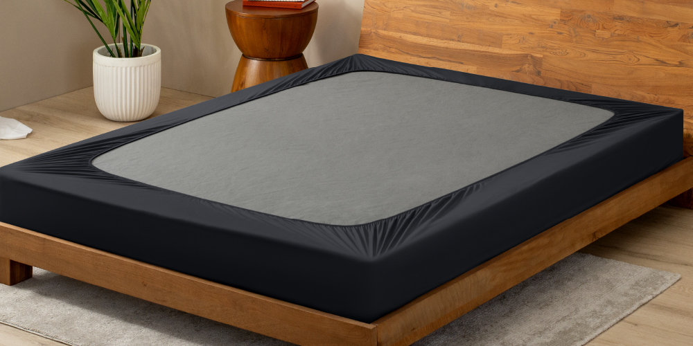 Box spring with a dark gray cover on a wood bed frame