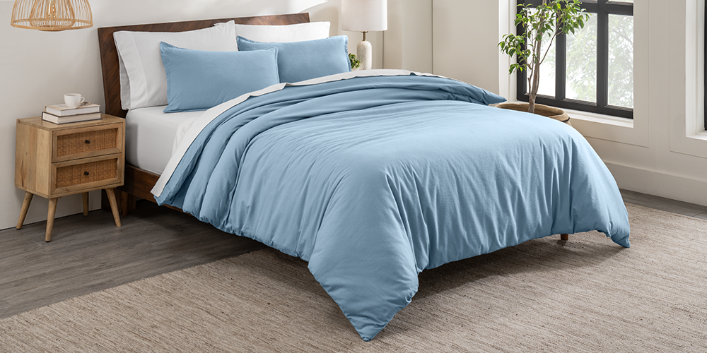 Bed with a blue cotton flannel duvet cover next to a wood nightstand