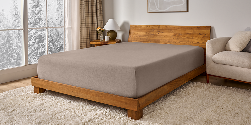 Bed with a gray flannel fitted sheet on a wood frame