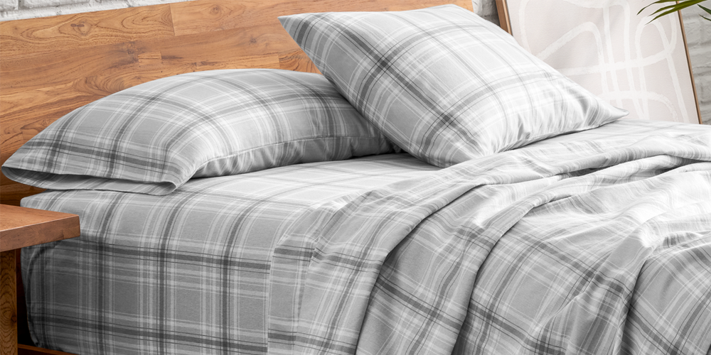 Close-up of a bed with light gray plaid flannel sheets