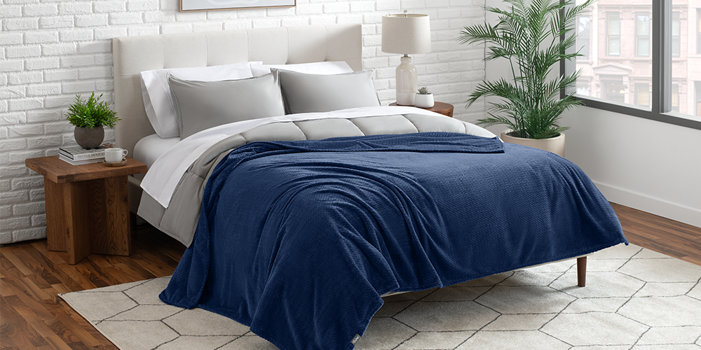Bed styled with navy blue Microplush Chevron Blanket in a bedroom