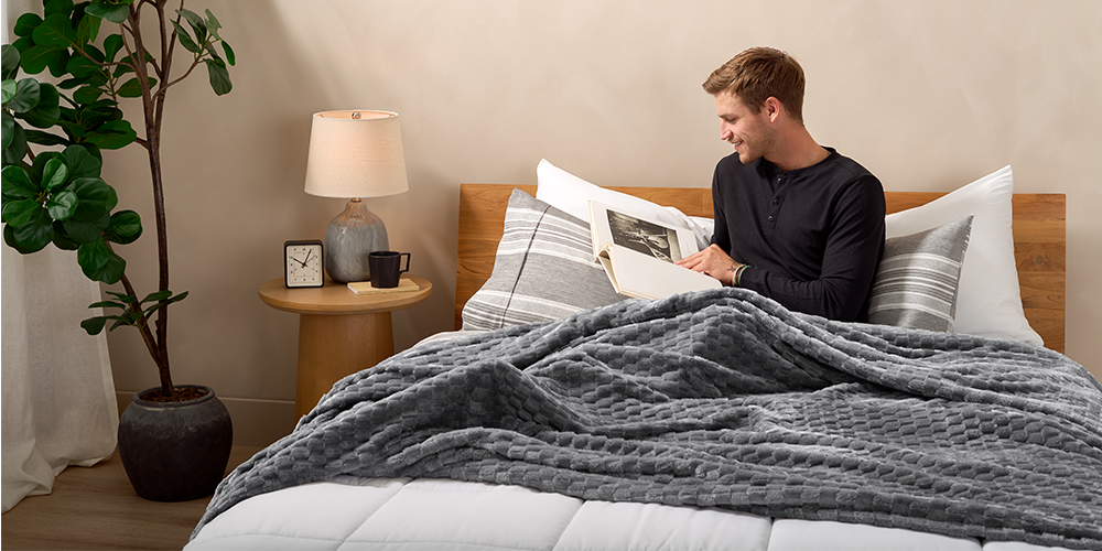 Bed with gray Microplush Waffle Blanket and man sitting nearby