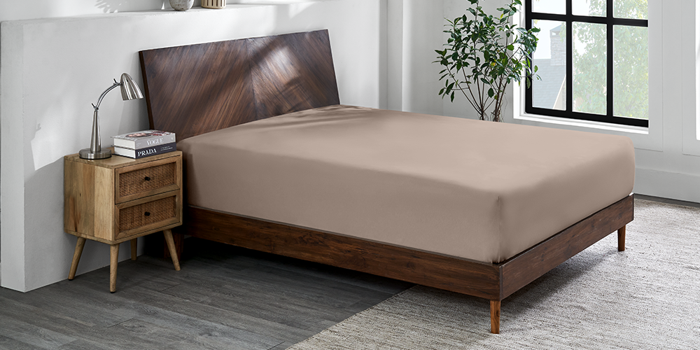 Bed with taupe Organic Cotton Jersey Fitted Sheet and dark wood bed frame in a bedroom
