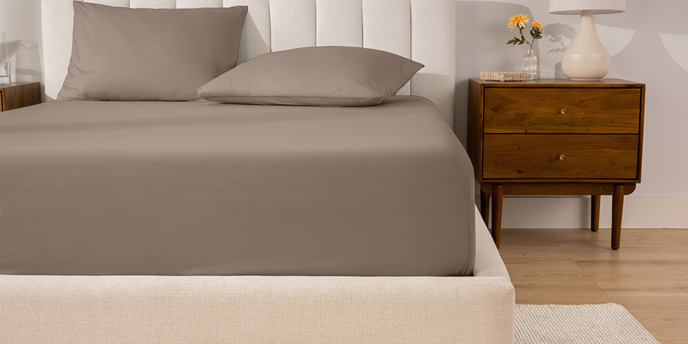 Bed styled with taupe Organic Cotton Percale Fitted Sheet and wood nightstand