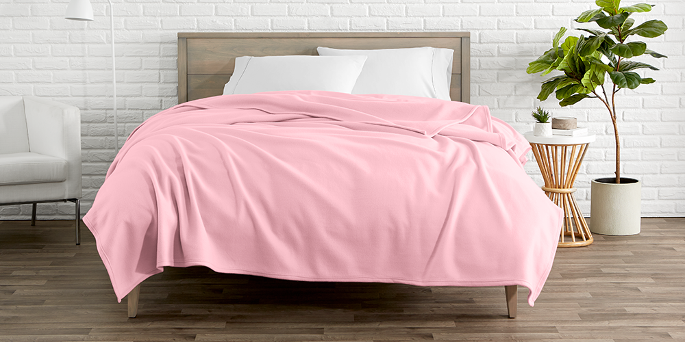 Bed styled with pink Polar Fleece Blanket, plant nearby