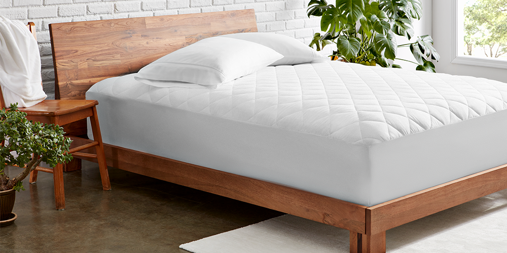Bed styled with white Quilted Mattress Pad and wood bed frame