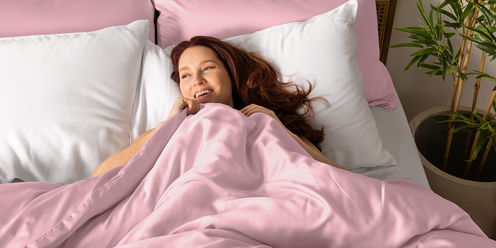 Woman lying in bed with pink bamboo sheets