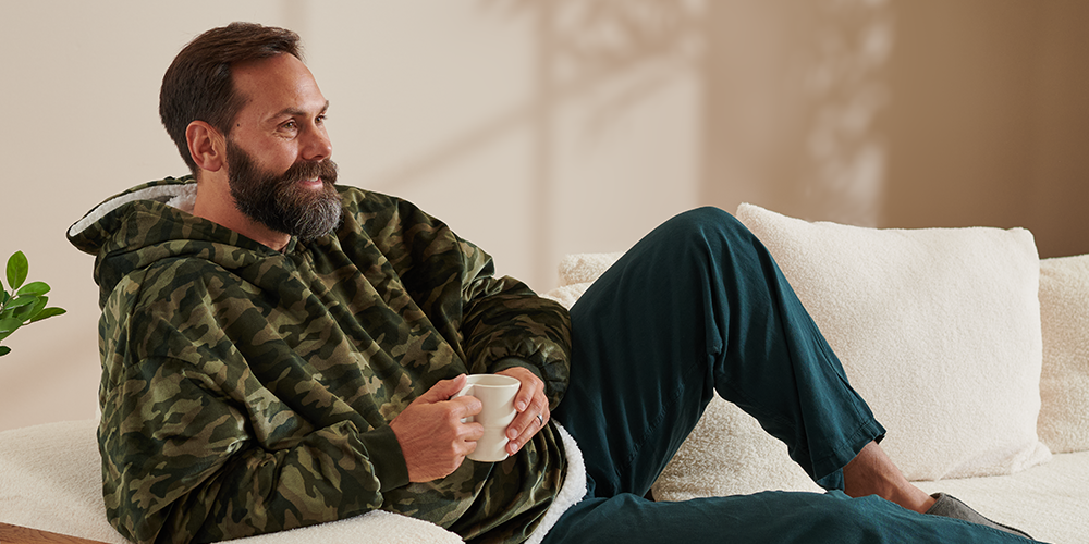 Man relaxing on a couch wearing a camo Bare Homey Wearable Blanket (Sherpa Adult)