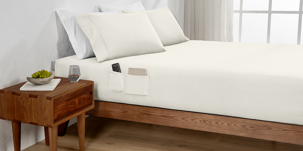 Bed styled with white Ultra Soft Dual Side Pocket Fitted Sheet and wood nightstand