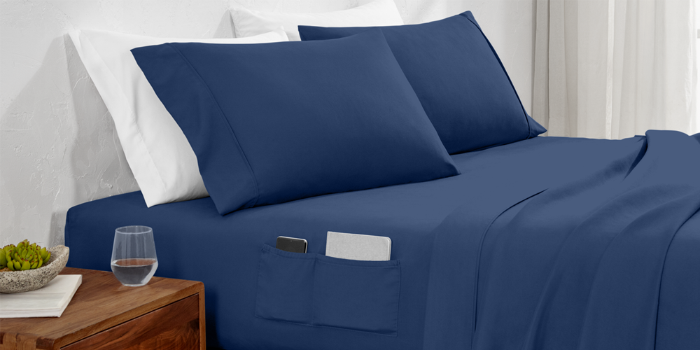 Bed styled with navy blue Ultra Soft Dual Side Pocket Sheet Set and wood nightstand