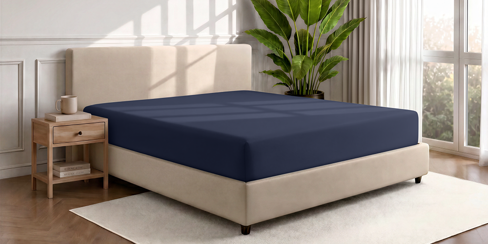 Bed styled with navy blue Ultra Soft Fitted Sheet, wood frame, plant nearby