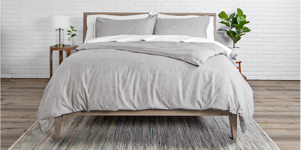 Bed styled with light gray heathered Ultra Soft Heather Duvet Cover Set, wood nightstand, plant nearby