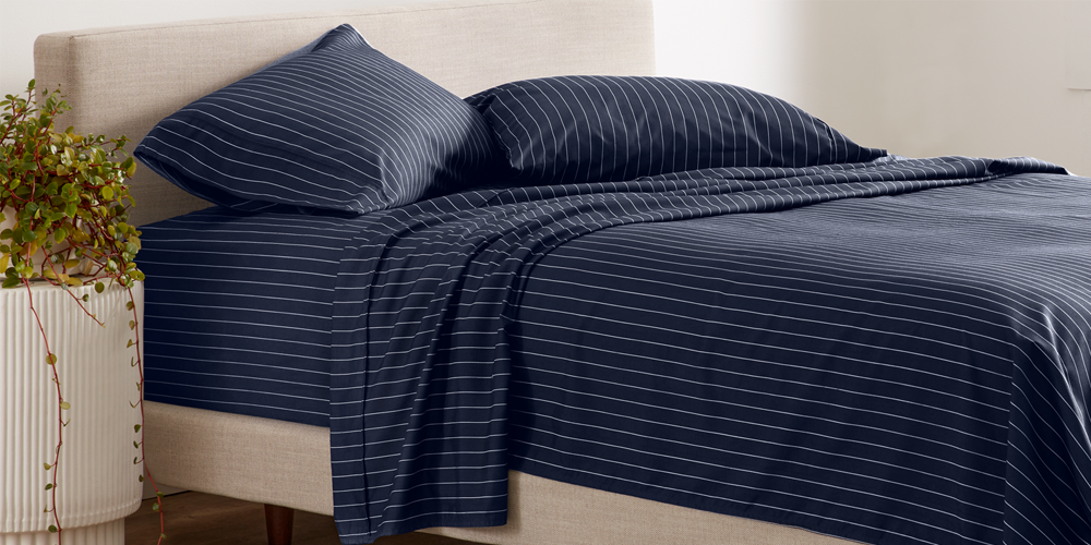 Bed styled with navy blue striped Ultra Soft Prints Sheet Set on a wood platform bed