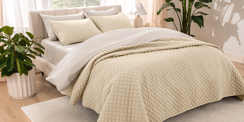 Bed styled with tan quilted Ultra Soft Quilt Set, plant nearby