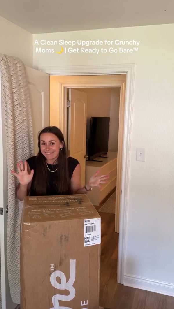 woman waving and smiling holding up a Bare Home Mattress Box