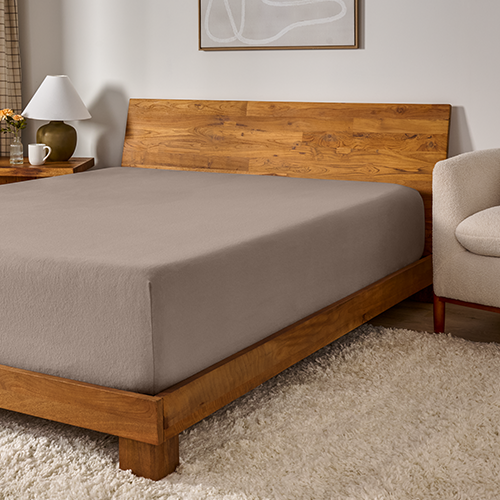 Bed with a gray flannel fitted sheet on a wood frame