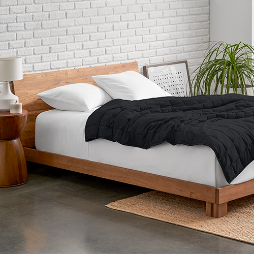 Bed with a black weighted blanket on a wood frame