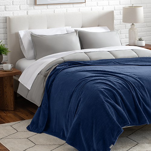 Bed with navy blue Microplush Chevron Blanket folded at the foot