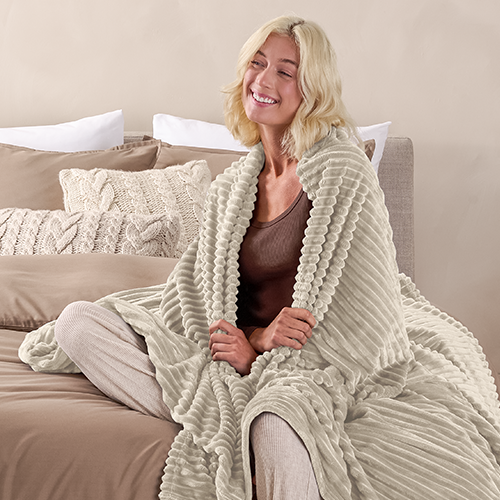 Person wrapped in cream Microplush Ribbed Blanket while sitting