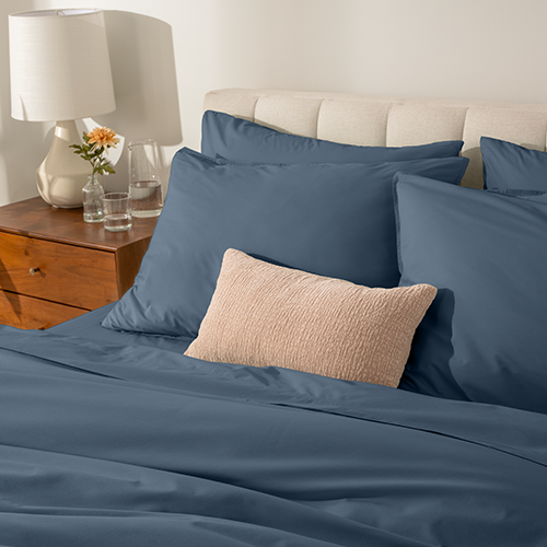 Bed styled with navy blue Organic Cotton Percale Bedding Bundle and tan pillow accent
