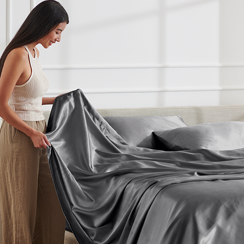 Woman sitting on a bed with a white satin sheet set