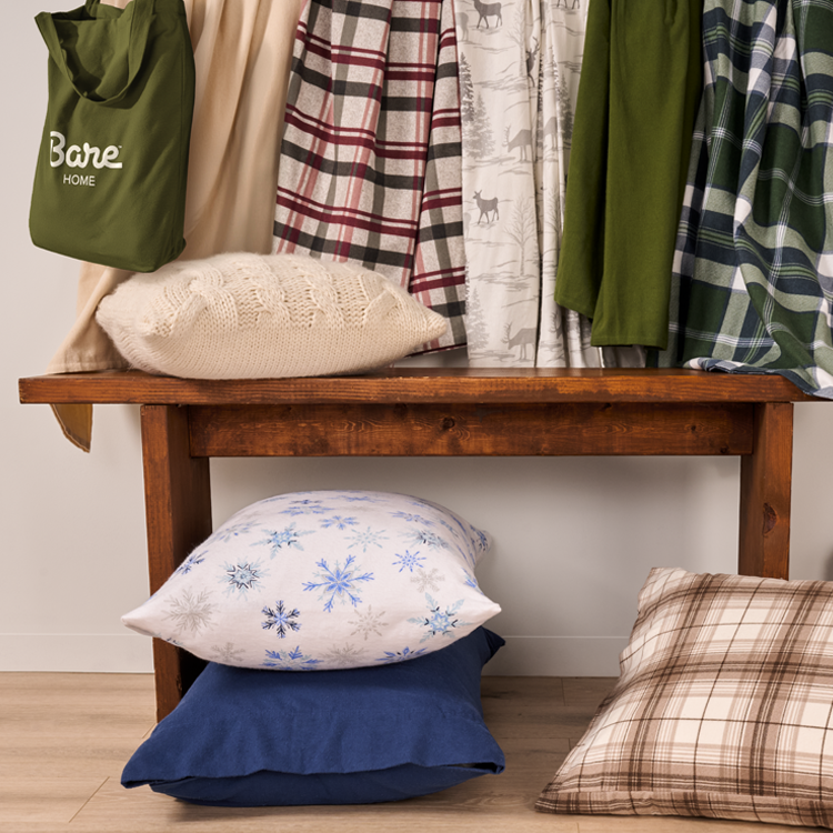 Wooden bench with pillows and plaid blankets in a room setting