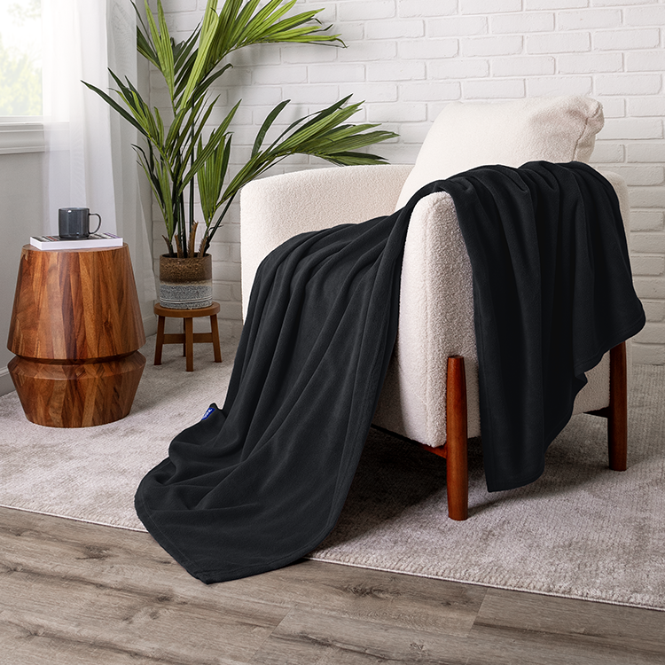 Chair with black Polar Fleece Blanket draped over it, plant nearby