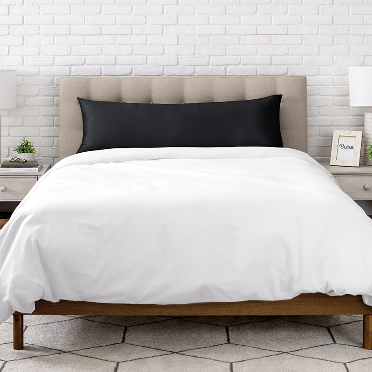 Neatly made bed with a white satin body pillowcase