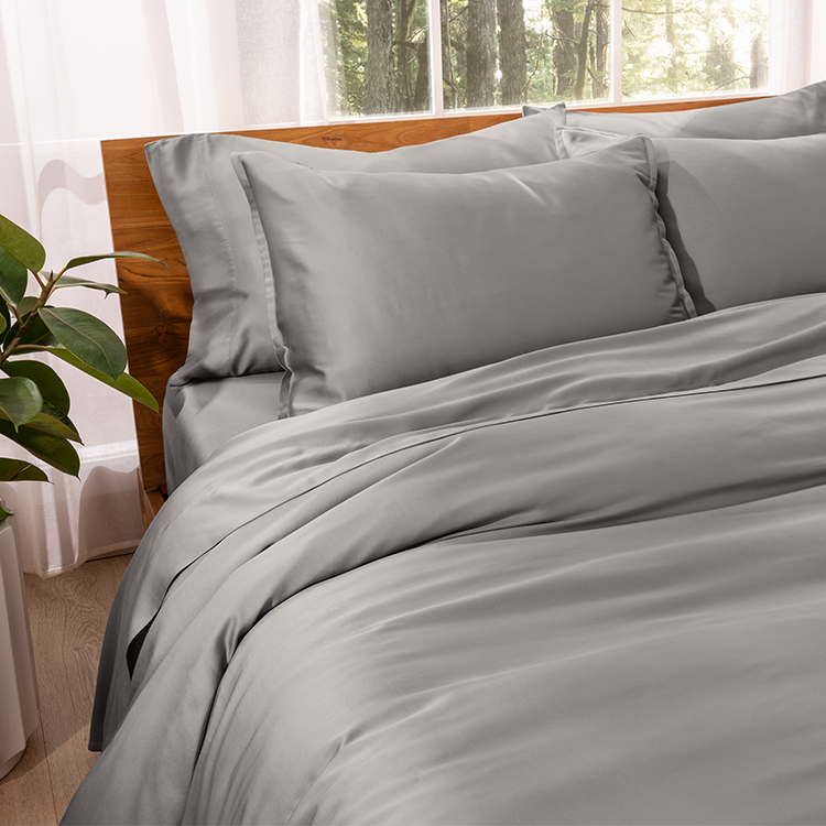 Bed styled with gray TENCEL Bedding Bundle, plant nearby