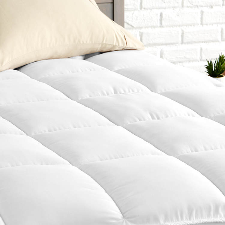 Closeup of white Reversible Mattress Pad fabric on a mattress