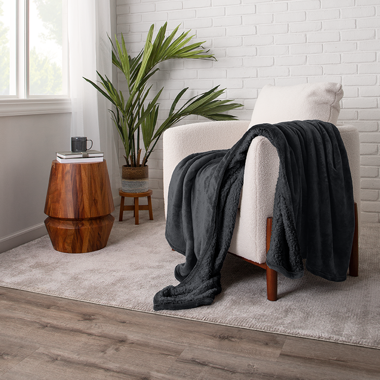 Chair with black Sherpa Blanket draped over it, plant nearby
