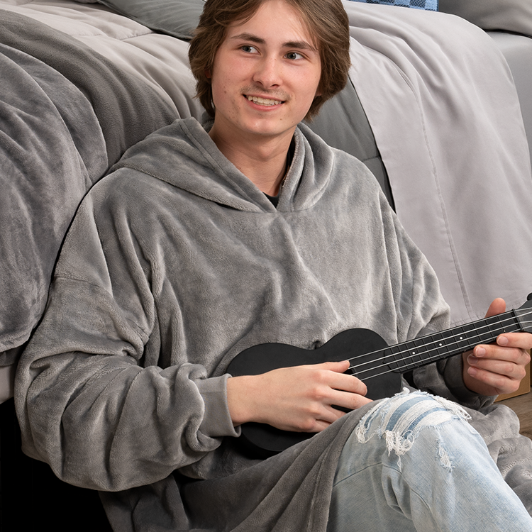 Man sitting while wearing a gray Bare Homey Wearable Blanket