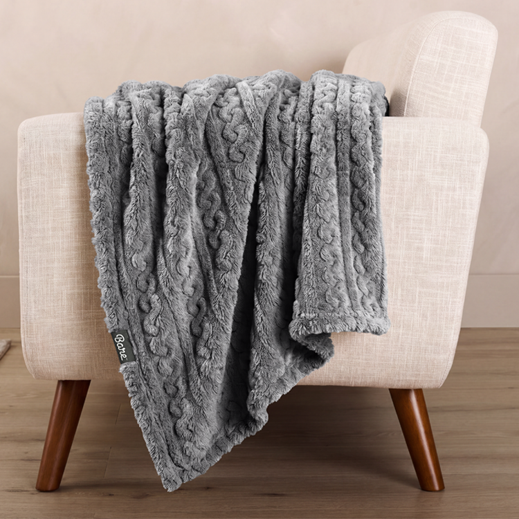 Gray cable knit faux shearling blanket draped on a chair
