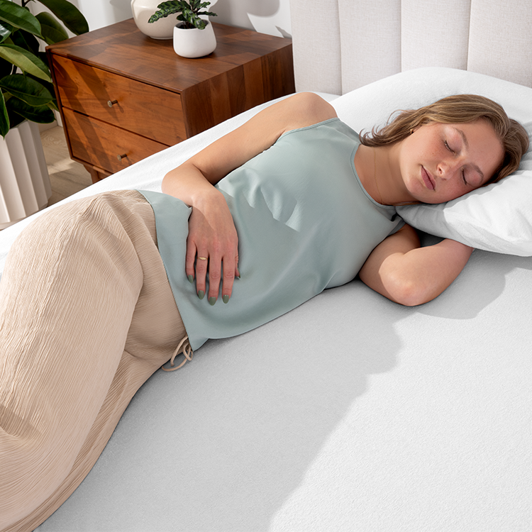 Woman lying on a bed with Cotton Terry Mattress Protector and gray sheets